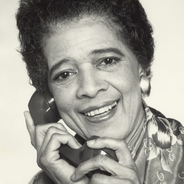 Head and shoulders portrait of Vel Phillips holding a telephone.
